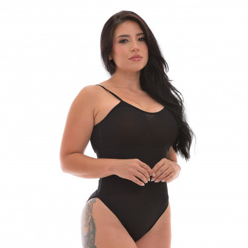 A woman with long dark hair and a thigh tattoo confidently models the Enzo Silueta Latina BODY CON TIRAS BEIGE/NEGRO against a plain white background.